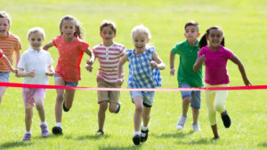 Group of children running through the ribbon to finish the race